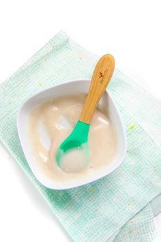 a wooden spoon is in a bowl of yogurt on a green napkin with sprinkles