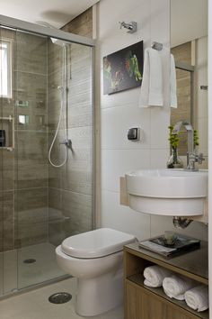 a white toilet sitting next to a walk in shower under a bathroom mirror above a sink