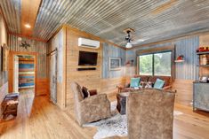 a living room filled with furniture and a flat screen tv on top of a wooden wall