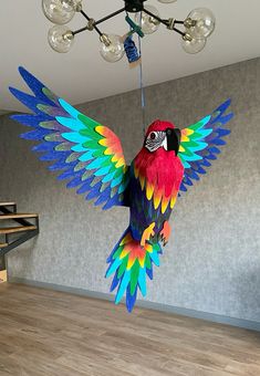 a colorful parrot hanging from the ceiling with its wings spread out and it's eyes open