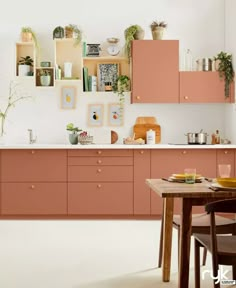 an image of a kitchen setting with pink cabinets and wooden table in the center area