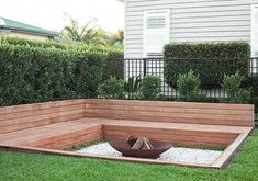 a wooden bench sitting on top of a lush green field next to a fenced in yard