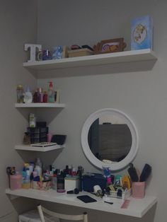 a white desk topped with lots of clutter next to a mirror and shelf filled with personal care items