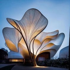 a large white sculpture sitting in the middle of a park next to a building at night