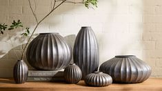 four vases sitting on top of a wooden table next to a potted plant