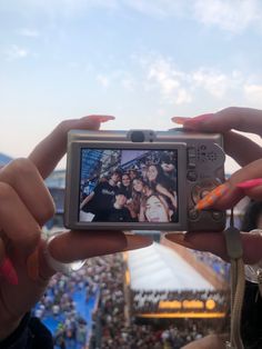 a person holding up a camera to take a photo in front of a large crowd