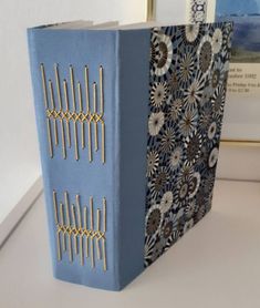 a blue book sitting on top of a white table next to a framed photo and an art piece