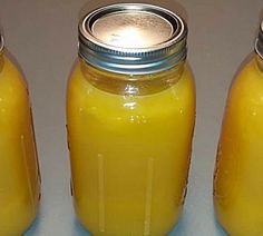 three jars filled with yellow liquid sitting next to each other