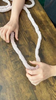 someone is making a snake out of sand on the table with their hands and fingers