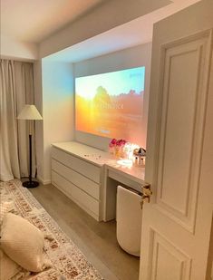 a bedroom with a bed, dressers and a flat screen tv on the wall