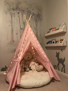 a pink teepee tent with two teddy bears in it and lights on the ceiling