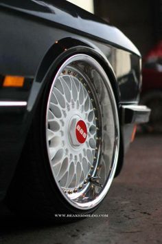 the front wheel of a black car with white spokes and red emblem on it