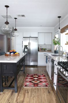 a kitchen with white cabinets and stainless steel appliances, including an area rug that matches the hardwood flooring