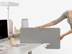 a woman is holding the back end of a computer case in front of her desk