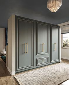 an empty room with gray cupboards and a chandelier hanging from the ceiling