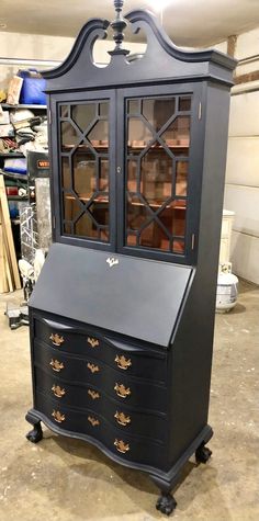 an antique black desk with glass doors and drawers