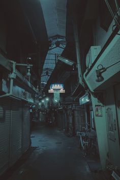 an alley way with lots of green lights on the ceiling and some bikes parked in front of it