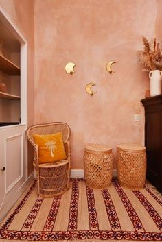 two wicker stools sit in front of a pink wall with gold sconces