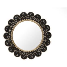 a round mirror sitting on top of a white wall next to a black and gold frame