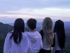 three girls standing on top of a hill looking at the sky