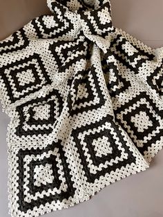 a black and white crocheted blanket on the floor