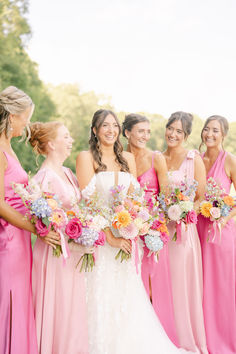 a group of women standing next to each other holding bouquets in their hands and smiling