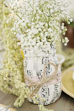 a vase filled with white flowers sitting on top of a table next to plates and napkins