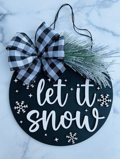 a black and white sign that says let it snow on top of a marble surface