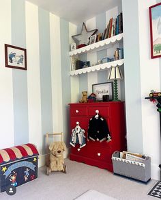 a child's room with striped walls and toys on the floor, including a toy chest