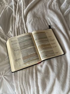 an open book sitting on top of a bed