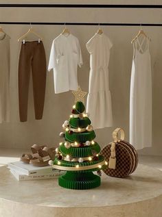 a green christmas tree sitting on top of a table next to clothes and purses