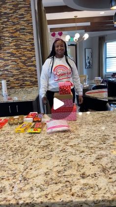 a woman standing in front of a kitchen counter with candy bags on top of it