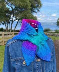 a woman wearing a blue jean jacket with a multicolored scarf on her neck