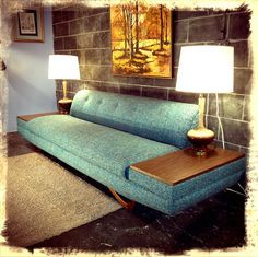 a blue couch sitting next to a lamp on top of a wooden table in a living room