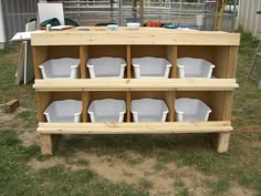 a wooden shelf filled with white dishes on top of grass