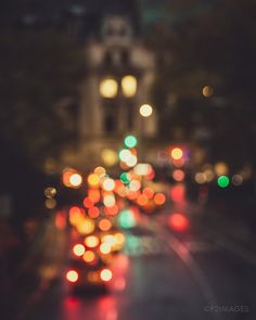 blurry photograph of city street at night with cars and buildings in the back ground