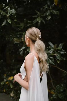 a woman with blonde hair wearing a white dress and holding her hand on her hip