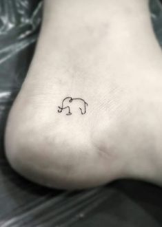 a small elephant tattoo on the side of a person's foot, which is black and white