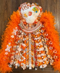 a teddy bear made out of orange feathers on a wooden floor with other items around it