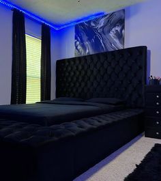 a black bed in a bedroom with blue lighting