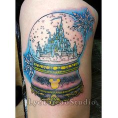 a snow globe with a castle in it on the side of a woman's thigh