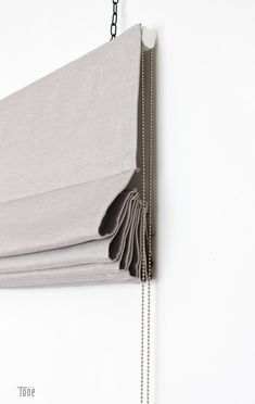 a close up of a curtain with chains hanging from it's side on a white wall