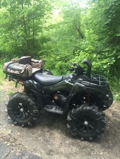 a black four - wheeler parked on the side of a road in front of some trees