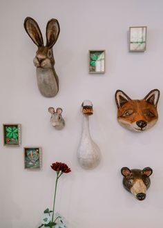 several animal heads mounted on the wall next to a vase filled with flowers and pictures