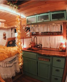 a small kitchen with lights on the ceiling and green cupboards in front of it