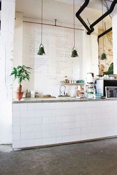 a kitchen with white tiles and hanging lights