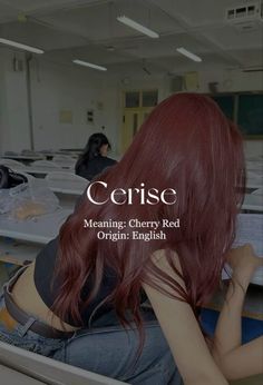 a woman with long red hair sitting in front of desks and looking at papers