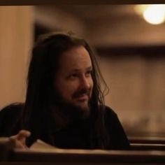 a man with long hair sitting at a table