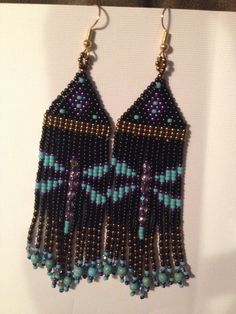 beaded earrings are hanging from hooks on a white surface with a black and blue background