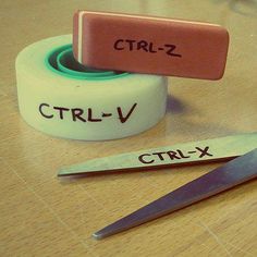 two rolls of tape and scissors on top of a wooden table with the words ctrl - v written on them